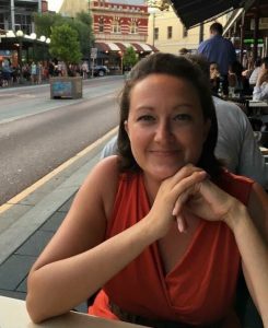 A picture of me smiling in an orange dress sitting at a table in Fremantle